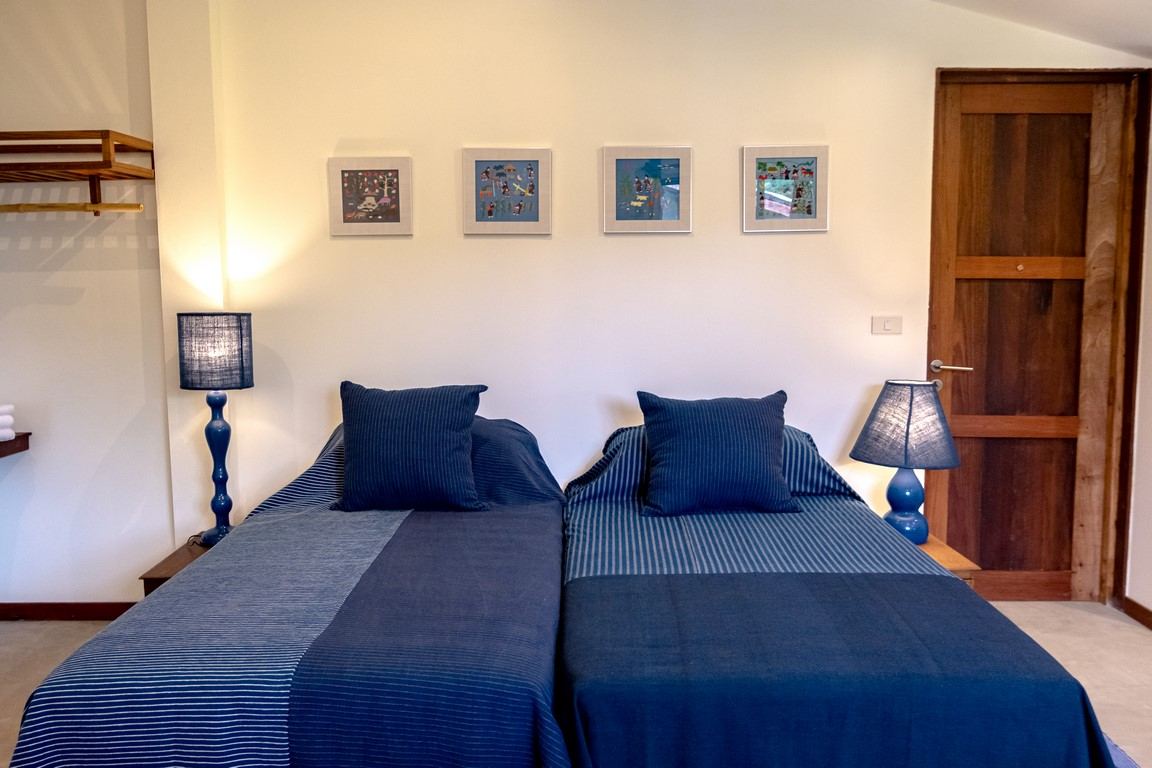 A twin-bed Nest room with framed textile art above the beds