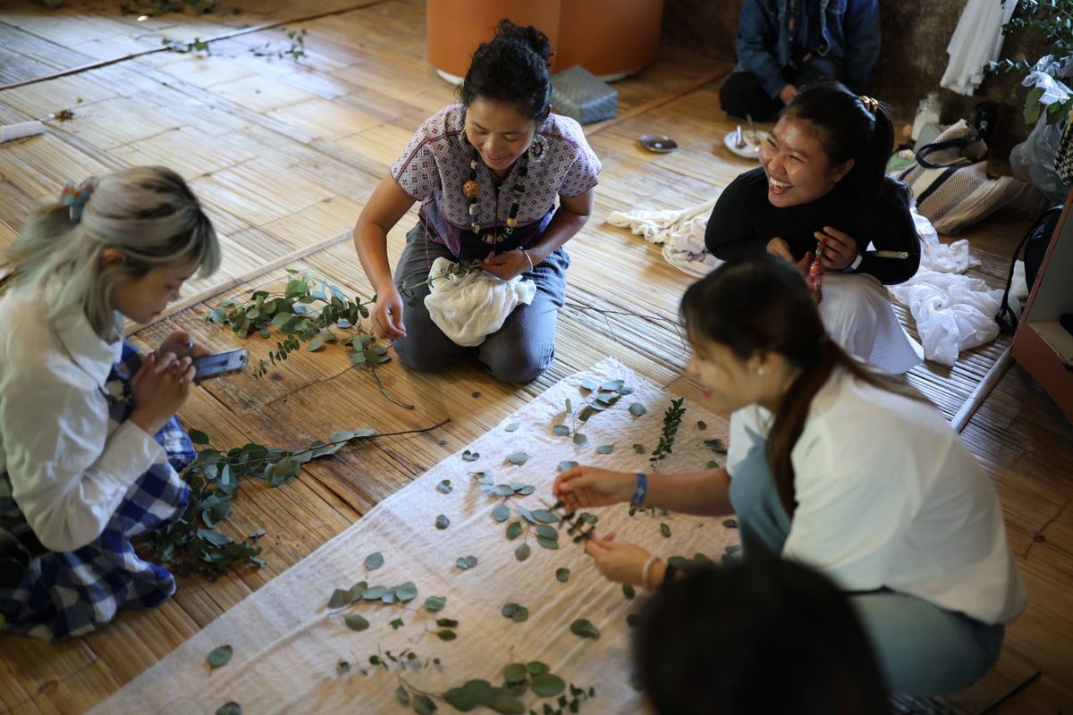 An eco-printing workshop: leaves laid out on cloth on the bamboo floor