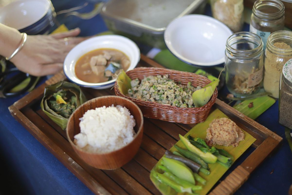 A set meal on a wooden tray: rice, curry, a basket of minced salad and fresh greens