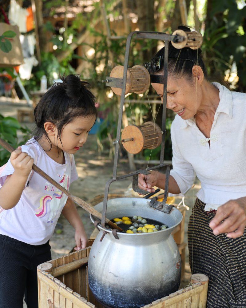 A grandmother and a child reeling silk from cocoons