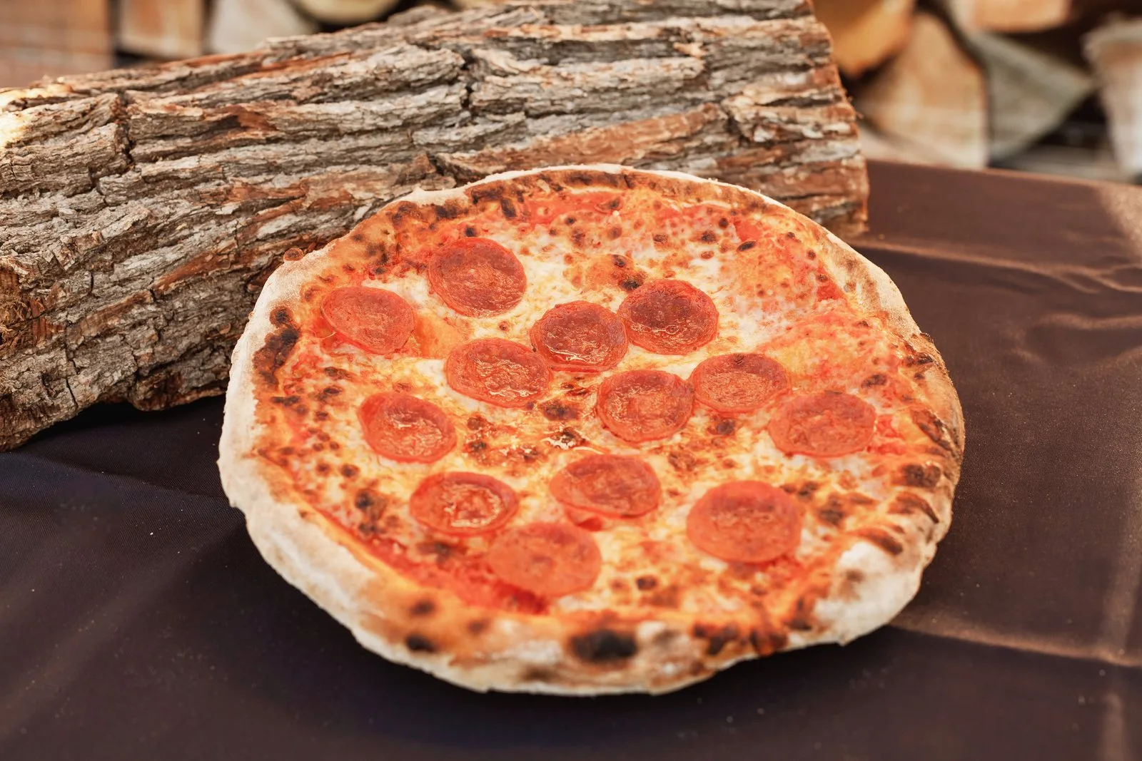 A pepperoni pizza fresh from a wood-fired oven