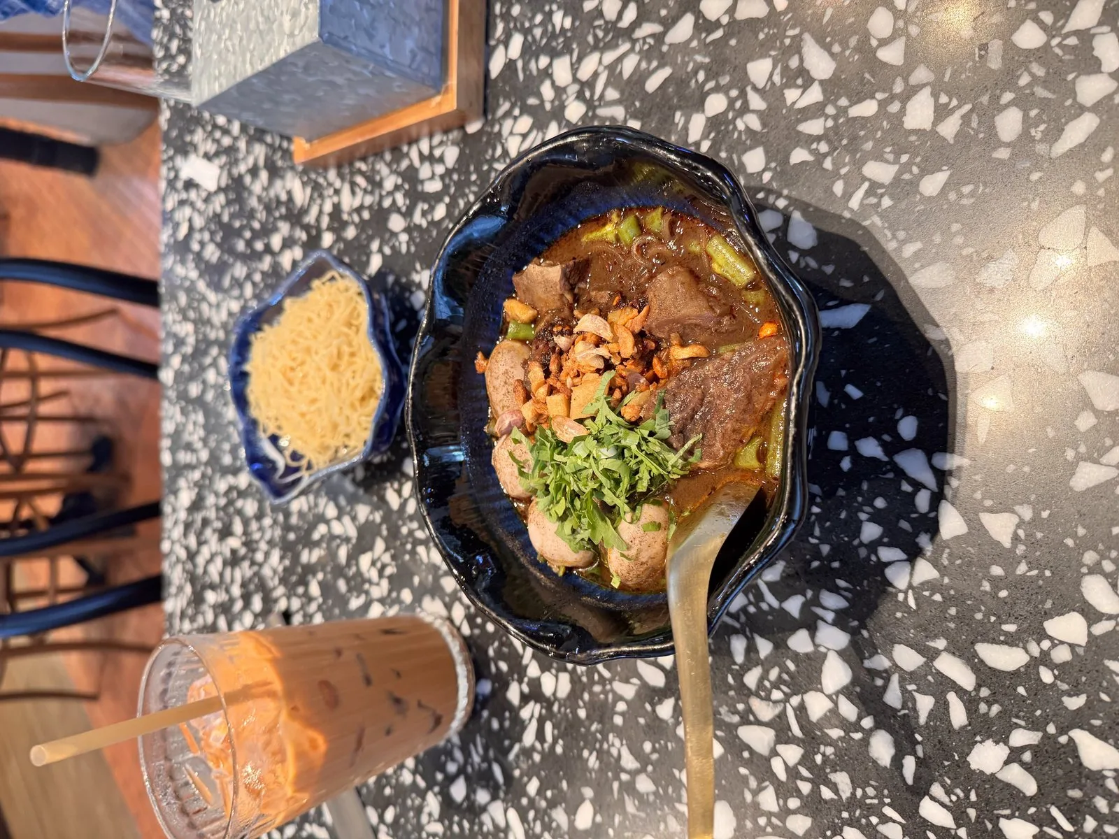 A bowl of Thai boat noodles with herbs and lime