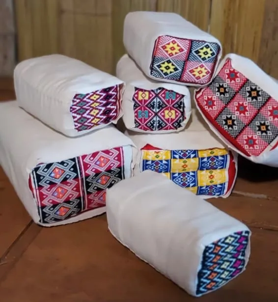 Small Mae Chaem–style pillows wrapped in patterned woven fabric at the Mae Hom stall